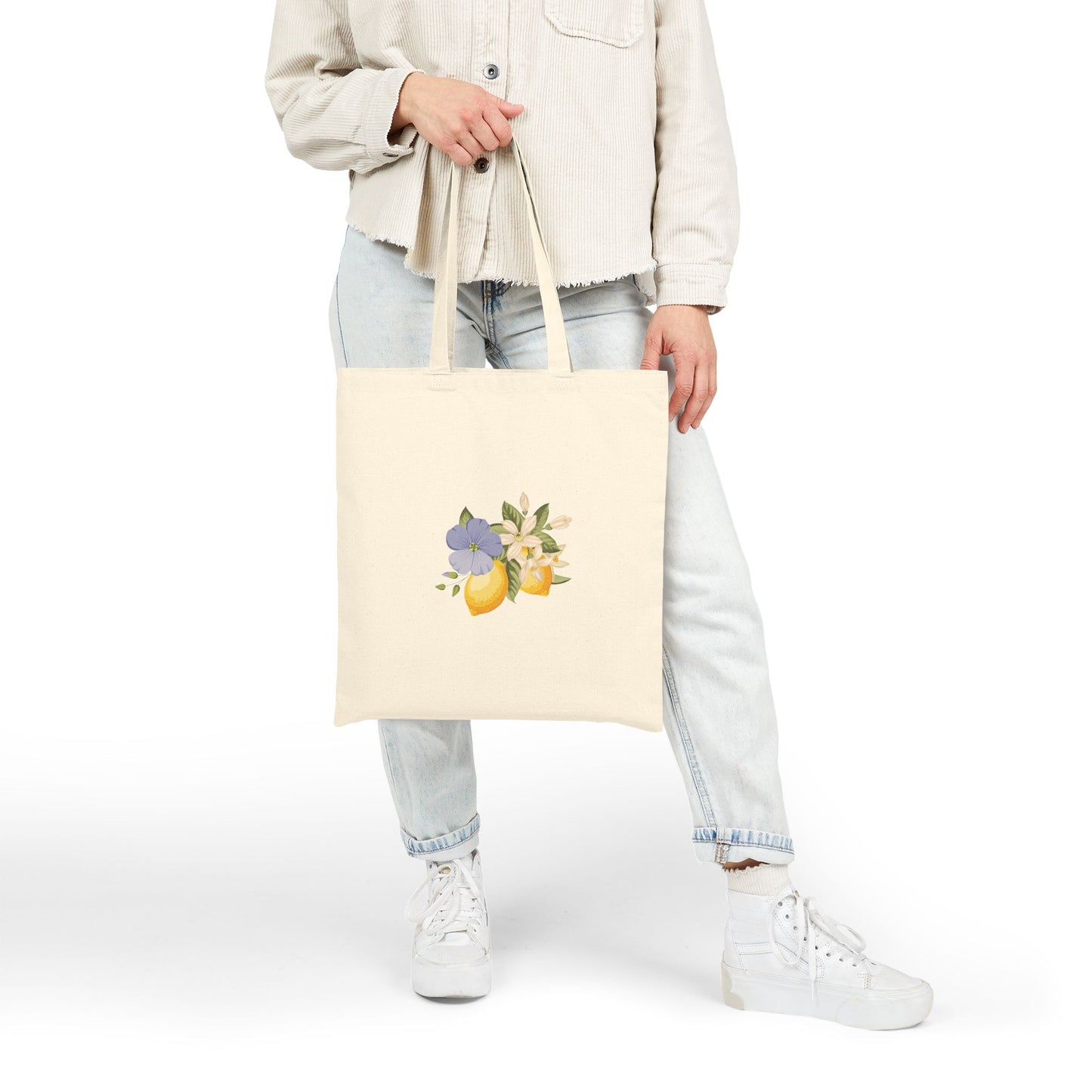 Model holding the lemon and violet floral canvas tote bag by its handles, close crop view