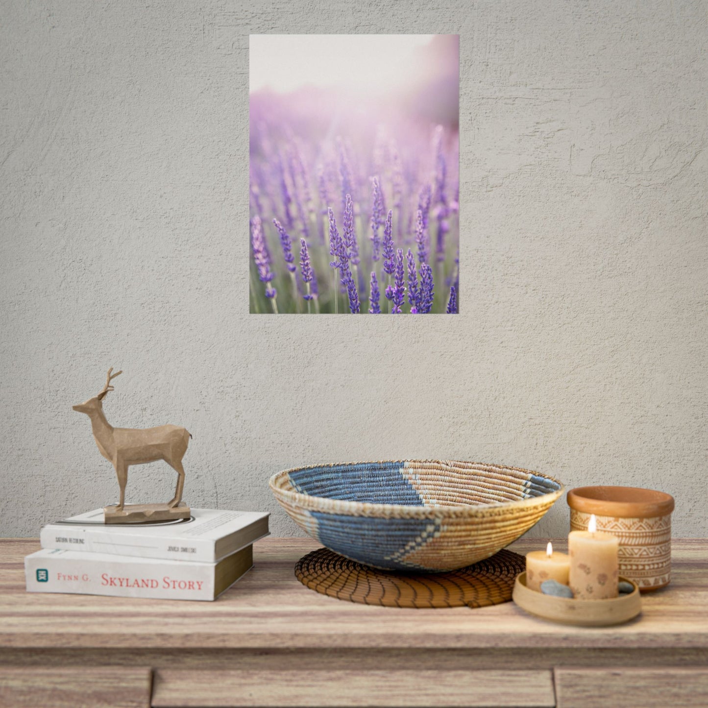 Framed lavender field poster mockup hanging above a shelf styled with decor and candles