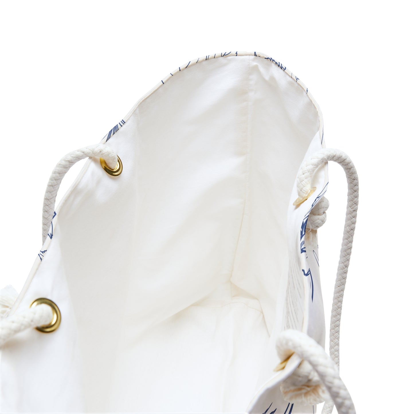 Close-up of the weekender bag interior lining showing cream fabric and brass grommet hardware on rope handles