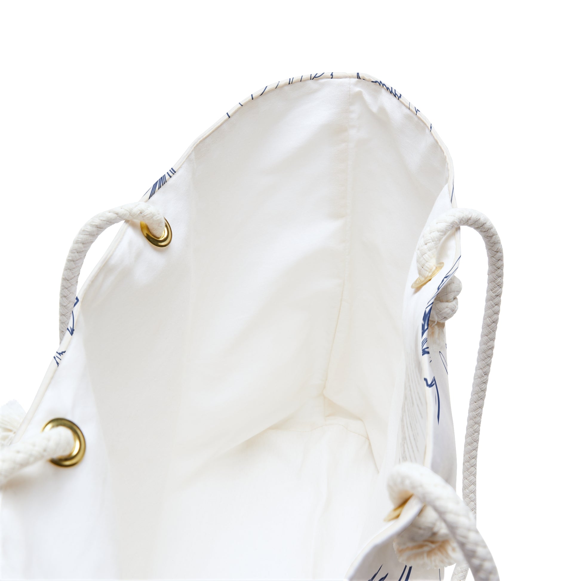 Close-up of the weekender bag interior lining showing cream fabric and brass grommet hardware on rope handles