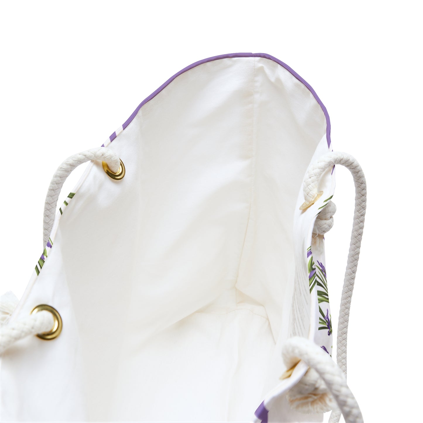 Close-up of the weekender bag's cream interior lining showing rope handle grommets with gold accents