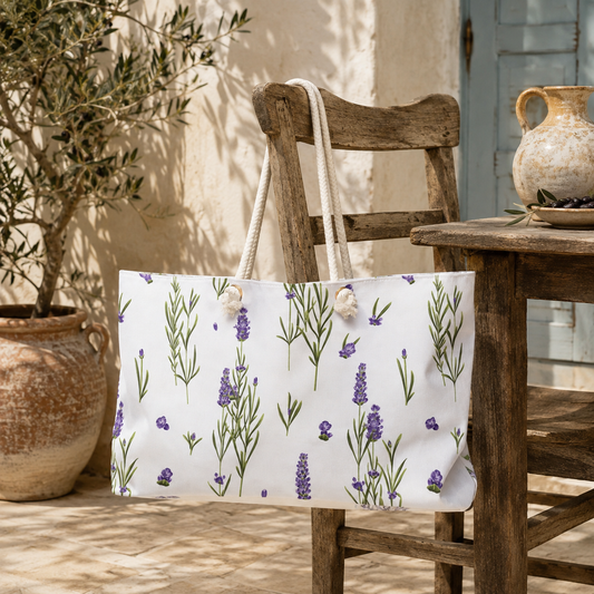 Lavender print weekender bag resting on a wooden chair beside a terracotta olive planter and jug on a sunlit stone patio