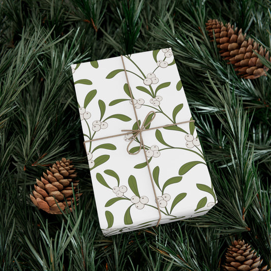Gift wrapped in mistletoe pattern paper on pine branches with pinecones