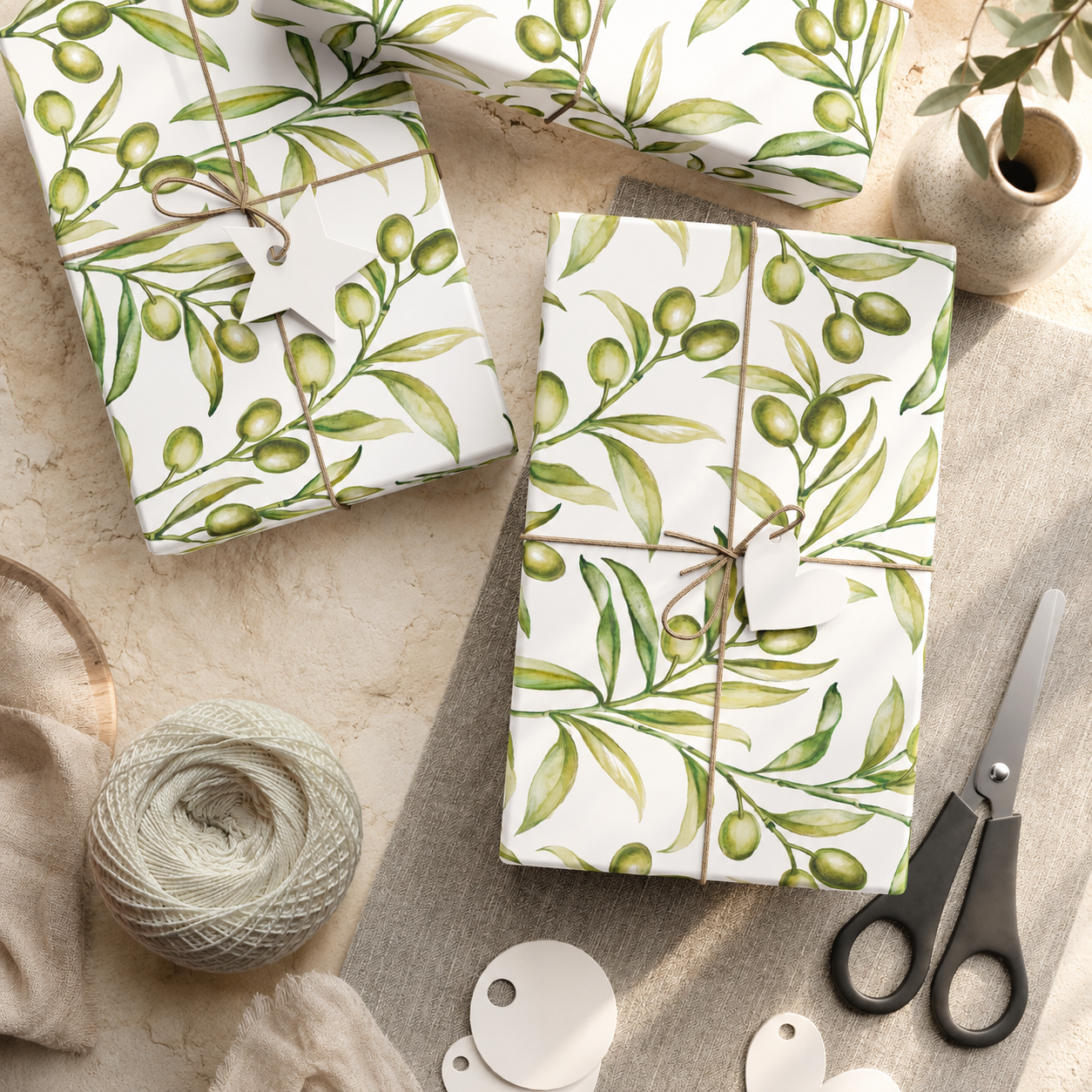 Folded olive branch gift wrap paper sheets tied with twine, styled with scissors and a linen napkin