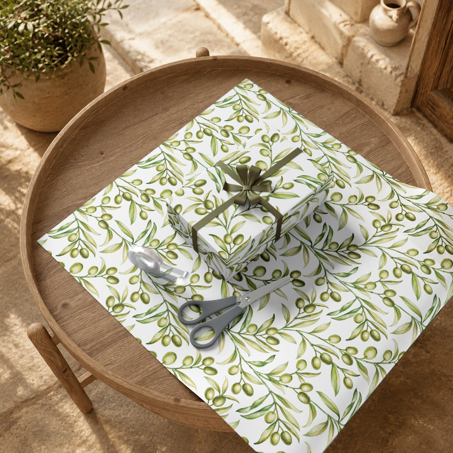 Wrapped gifts in olive branch gift wrap paper displayed on a wood tray with a potted olive branch