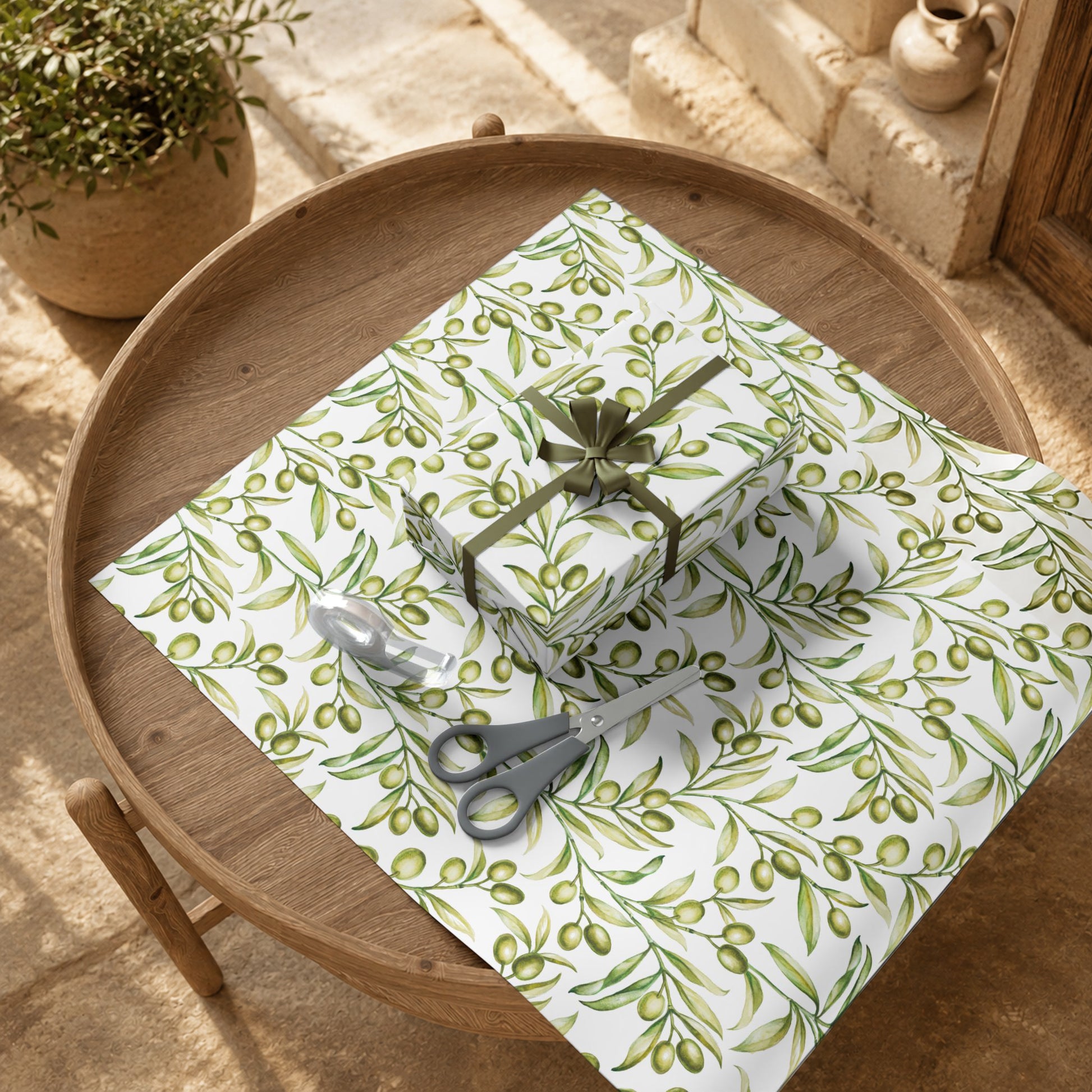 Wrapped gifts in olive branch gift wrap paper displayed on a wood tray with a potted olive branch