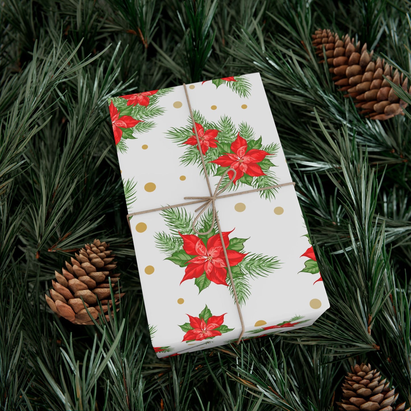 Wrapped gift in poinsettia and gold dot Christmas gift wrap paper resting on evergreen branches and pinecones