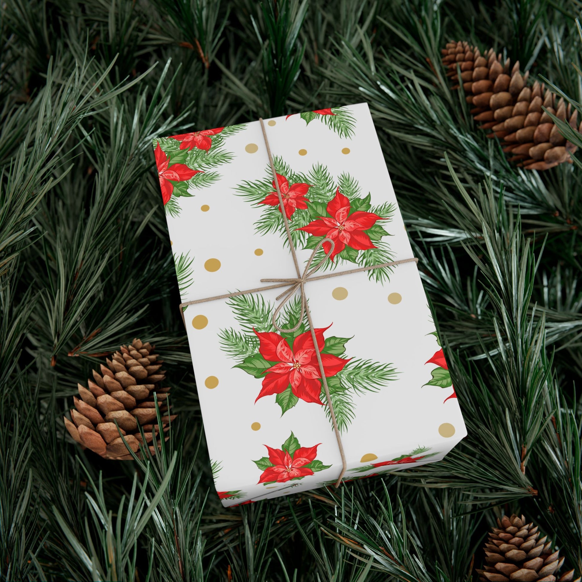 Wrapped gift in poinsettia and gold dot Christmas gift wrap paper resting on evergreen branches and pinecones