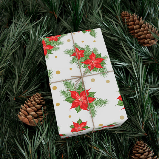 Wrapped gift in poinsettia and gold dot Christmas gift wrap paper resting on evergreen branches and pinecones