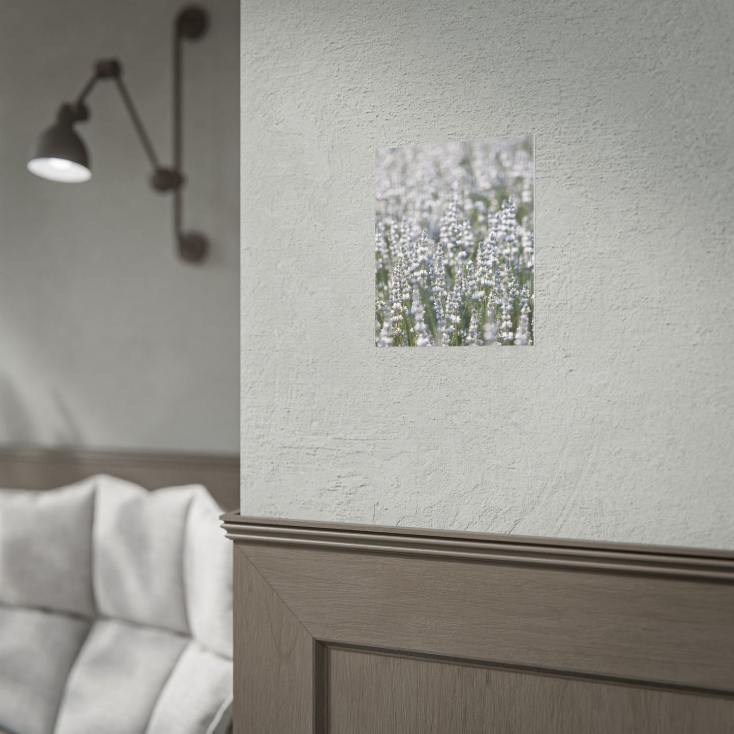 White lavender botanical print on a dark wall beside a sconce light in a minimal bedroom